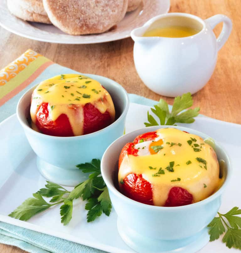 Light blue cups filled with Baked Eggs in Tomatoes with Easy Blender Hollandaise Sauce