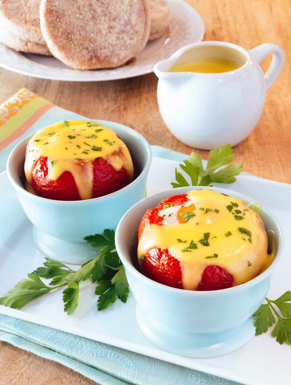 Light blue cups filled with Baked Eggs in Tomatoes with Easy Blender Hollandaise Sauce