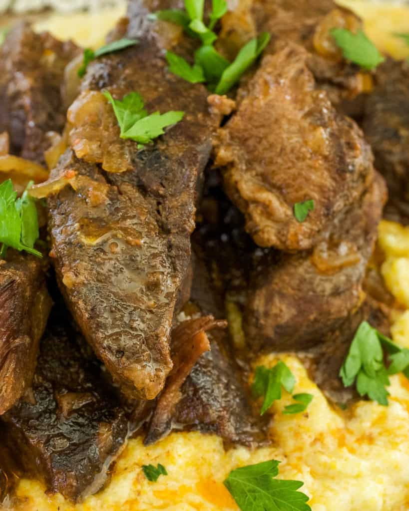 close up shot of cooked Beef Short Ribs sitting on Creamy Parmesan Polenta