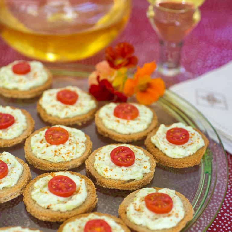 Platter filled with Benedictine Cheese Canapes and wine in the background