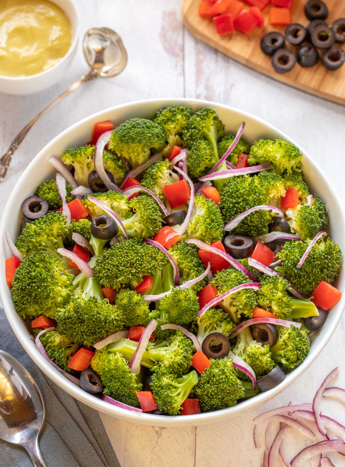 Oval white bowl holding Best Broccoli Salad with Caesar Dressing on the side