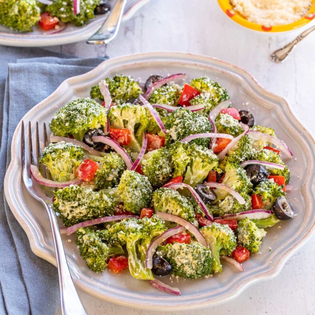 Blue plate displaying Best Broccoli Salad, with additional Parmesan Cheese on the side