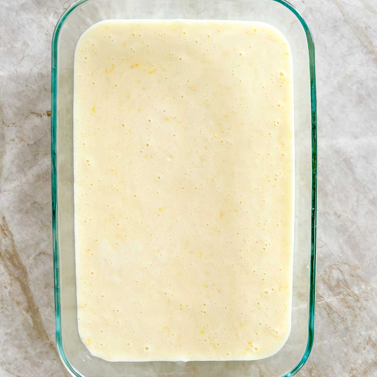 Unbaked lemon filing in baking dish on top of baked crust