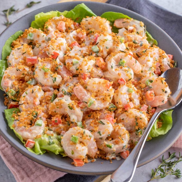 blue plate showing Shrimp Salad with Lime Herb Dressing; a serving spoon on the side