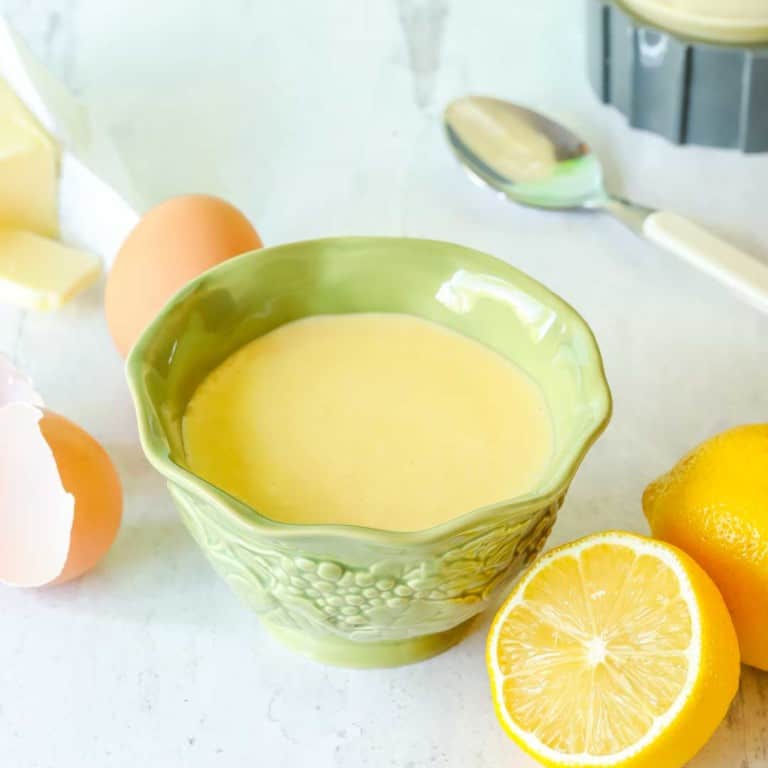 Small green bowl holding Hollandaise Sauce, surrounded by sauce ingredients