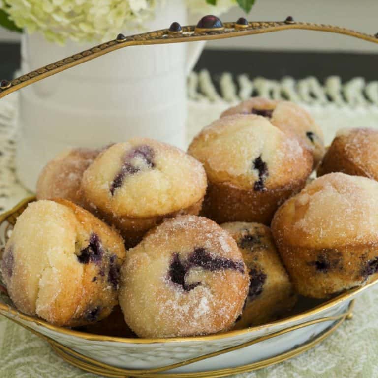 white basket filled with Lemon Blueberry Muffins, with flowers in the background