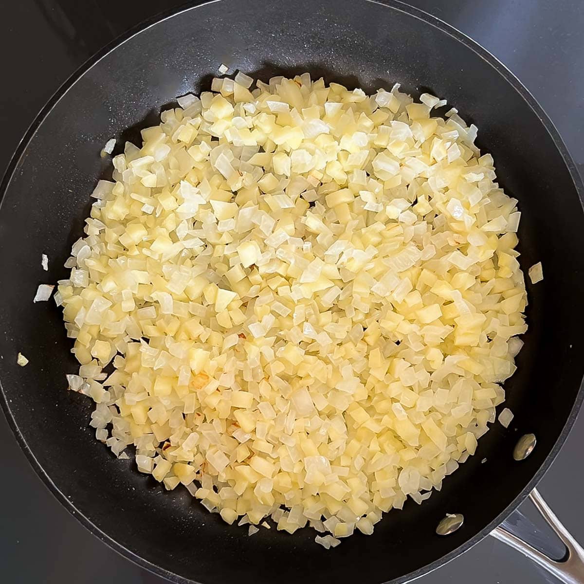 Chopped onion and apple sauteing in a large skillet