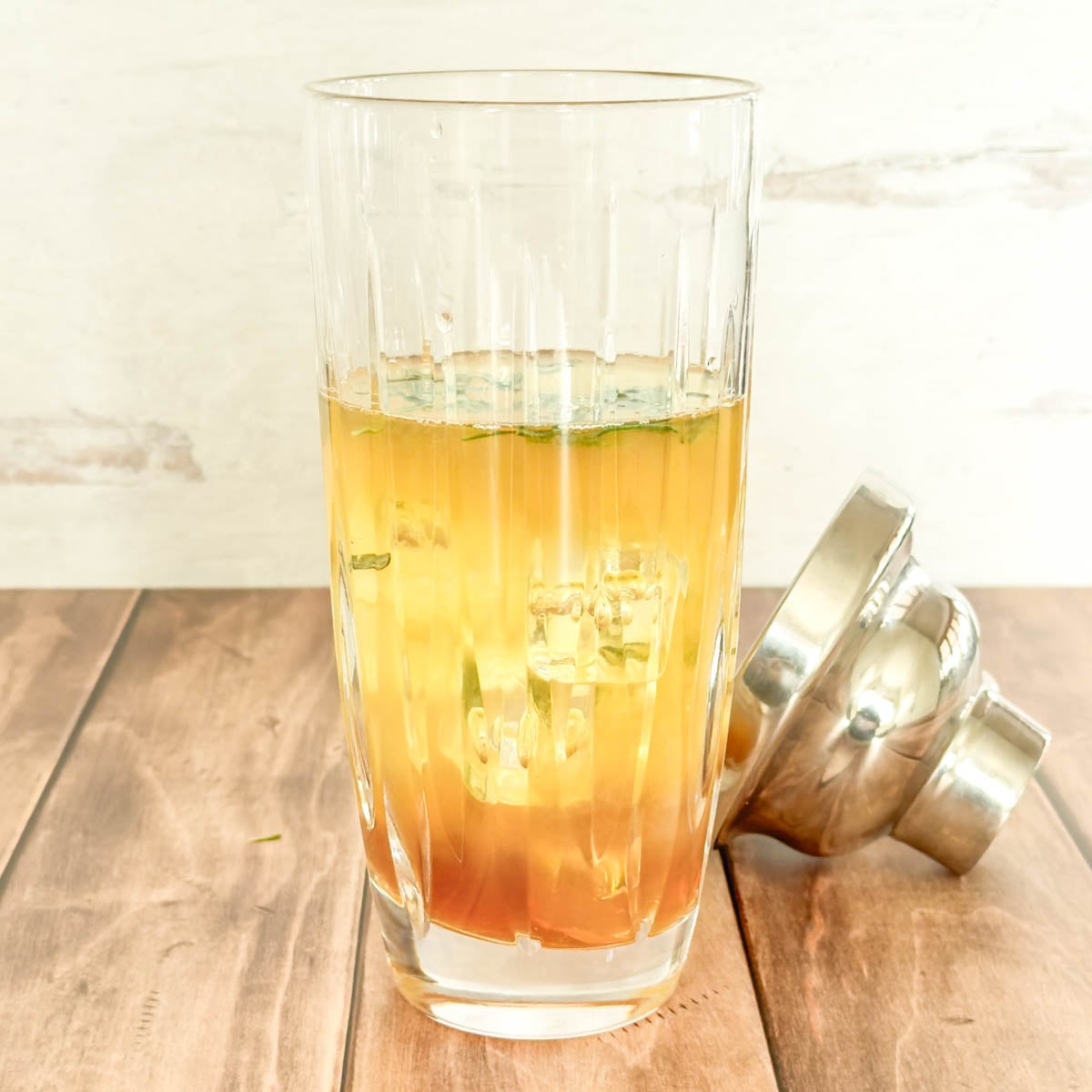 Side view of glass cocktail shaker with all lemon whiskey cocktail ingredients added, with ice.