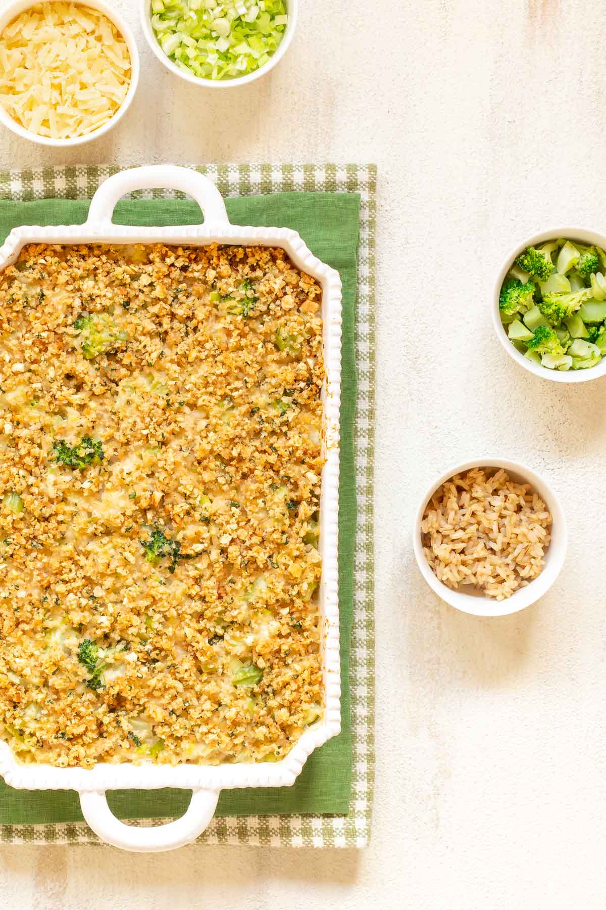 Overhead view of Cheesy Broccoli Rice Casserole, with bowls of cheese, onion, broccoli and rice on the side