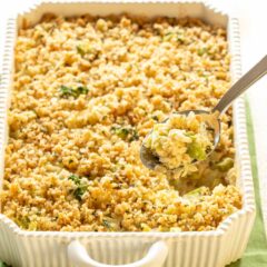 Spoon holding some Cheesy Broccoli Rice Casserole, hovering over the rest of the casserole