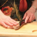 Step one of butterflying a chicken breast - slicing from the side with hand on top