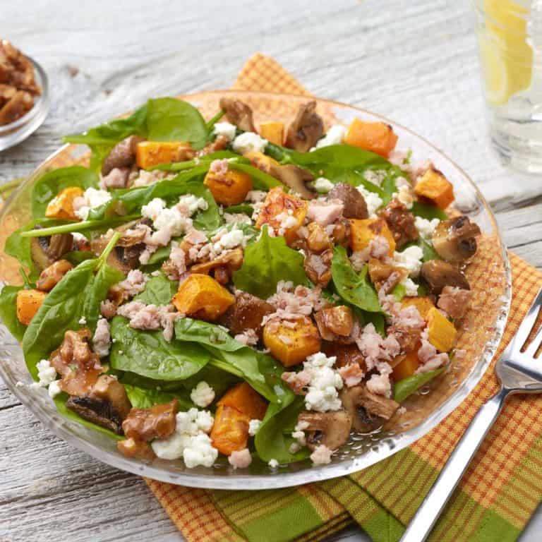 Roasted buttrnut squash and mushroom spinach salad in a glass bowl