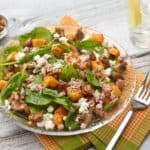 Roasted butternut squash and mushroom spinach salad ina glass bowl