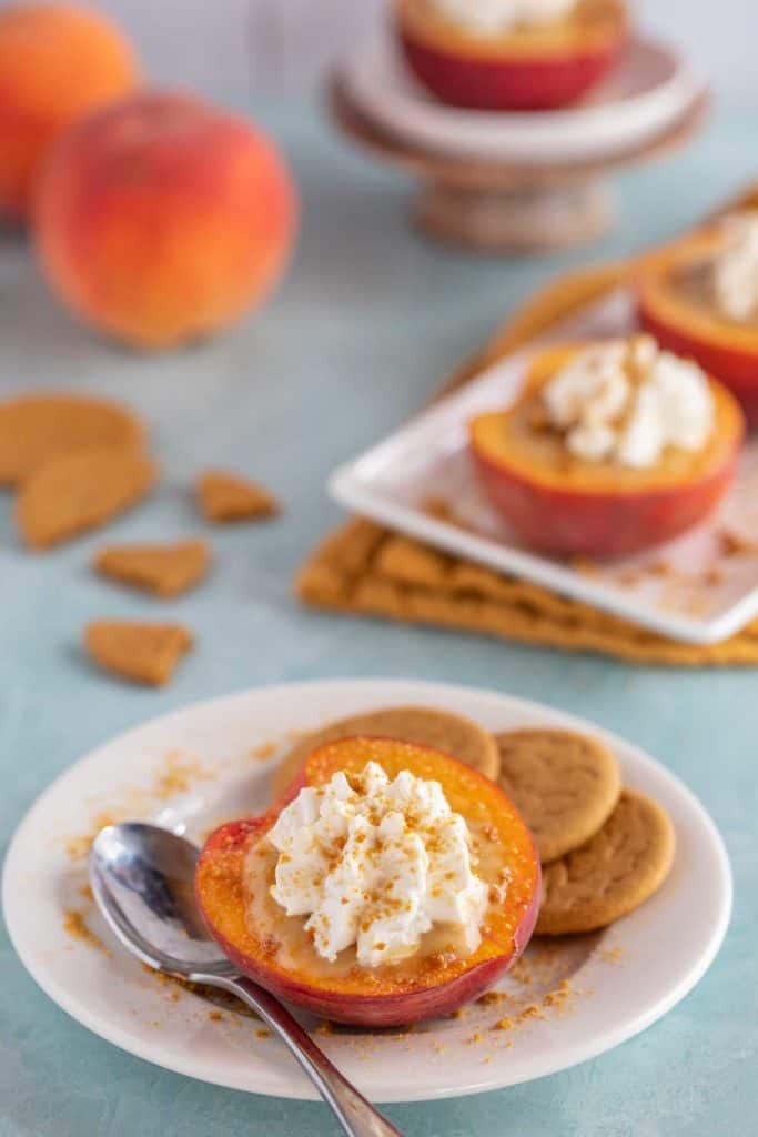 White platter holding Butterscotch Pudding Filled Peaches, with whole peaches in the background