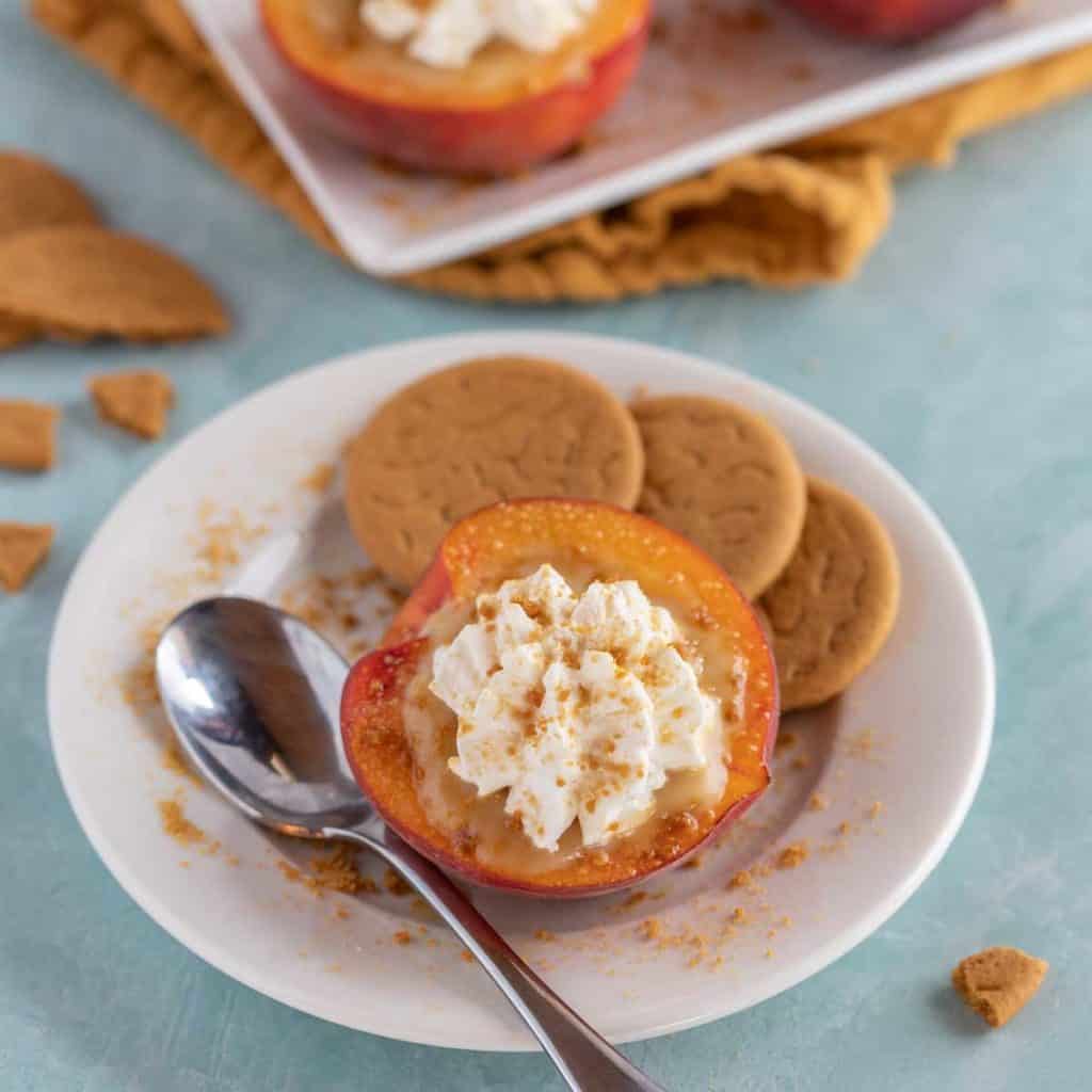 White plate holding one Butterscotch Pudding Filled Peach, with gingersnaps on the side