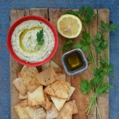 bowl of Cannellini Dip with Truffle Oil on a board with pita chips