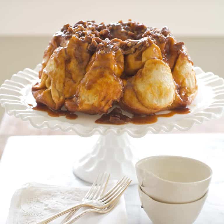 White cake stand holding Overnight Bundt Caramel Rolls