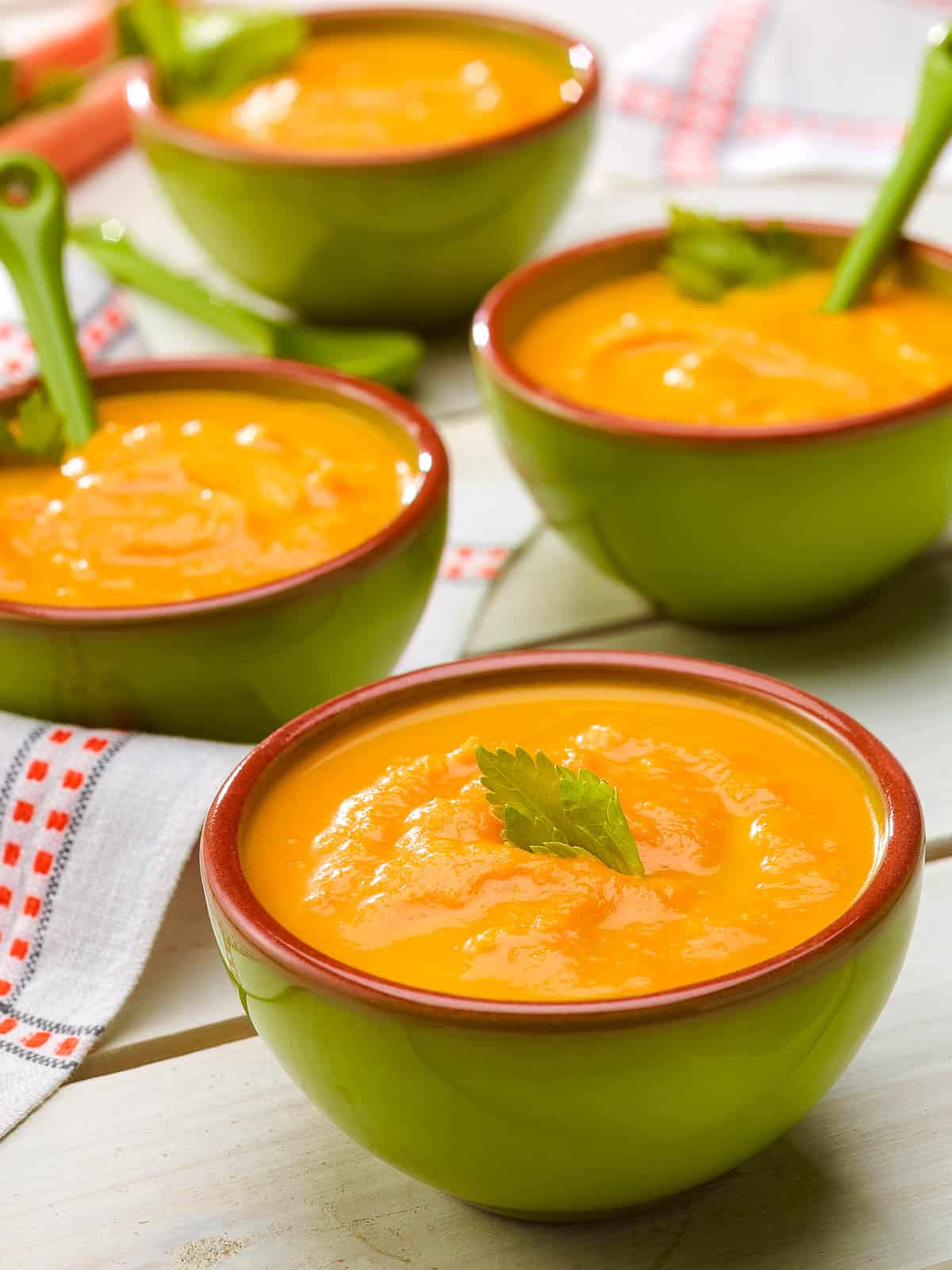 three bowls showing 3 servings of Creamy Carrot Ginger Soup.