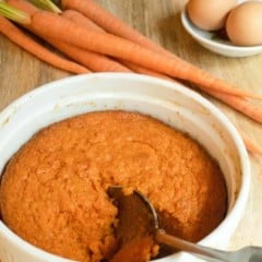 white dish of Roasted Carrot Souffle, with a spoon scooping out a portion