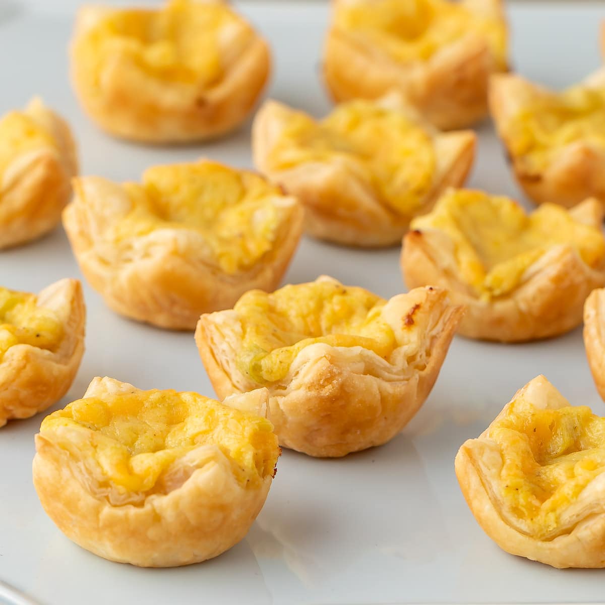 Close up of 11 Mini Cheese Tarts on a light blue platter