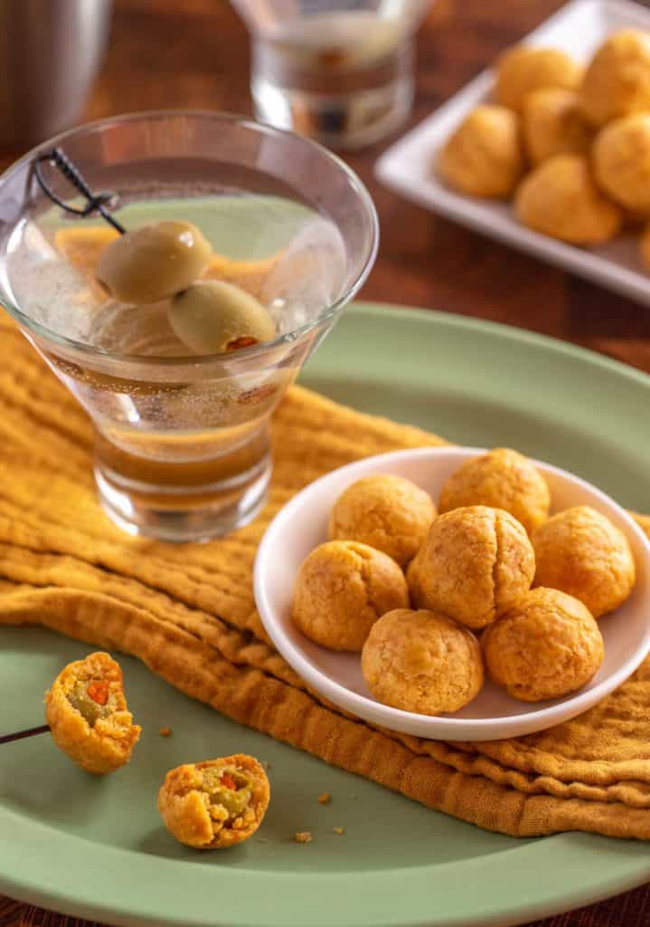 Green platter underneath a yellow napkin, martini and small bowl of Olive Cheese Balls