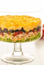 side view of a trifle dish filled with Shredded Chicken Taco Salad, with the ingredients arranged in layers