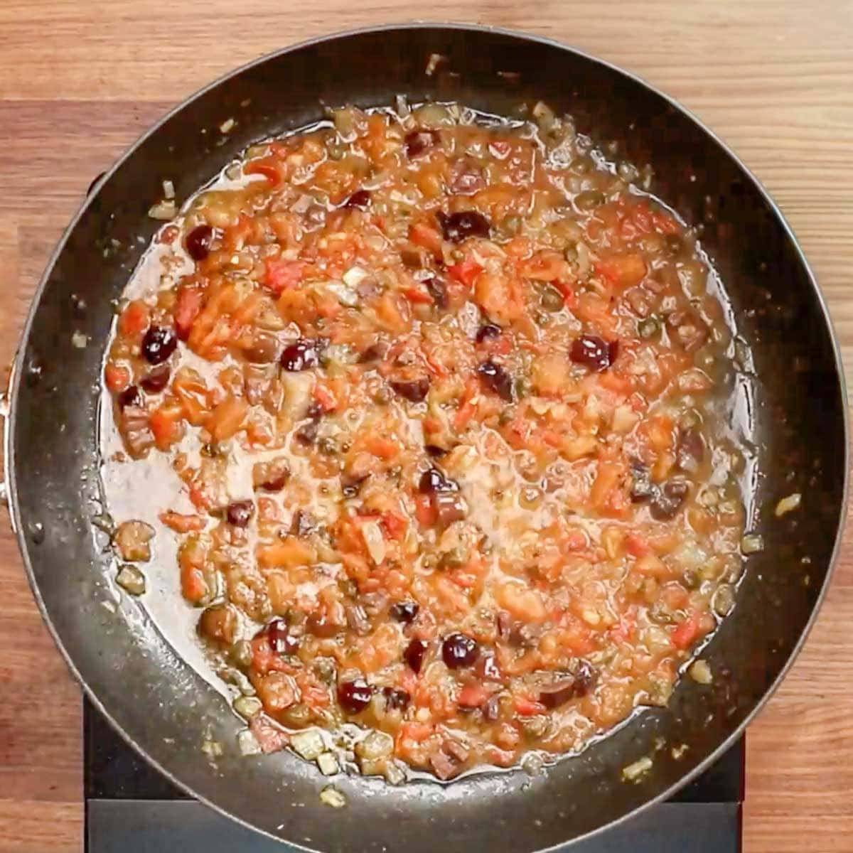 Tomato and olive sauce cooking in a skillet. 