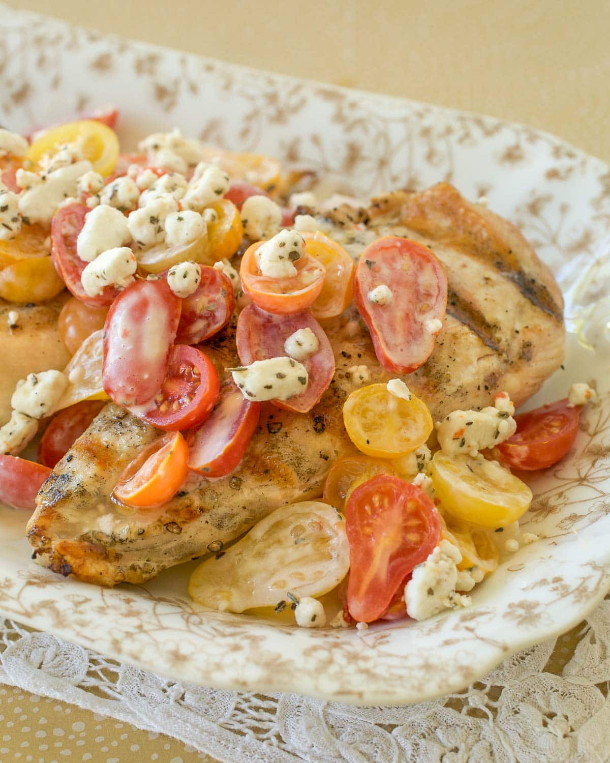 Gold and white platter holding Grilled Chicken with Tomatoes and Goat Cheese