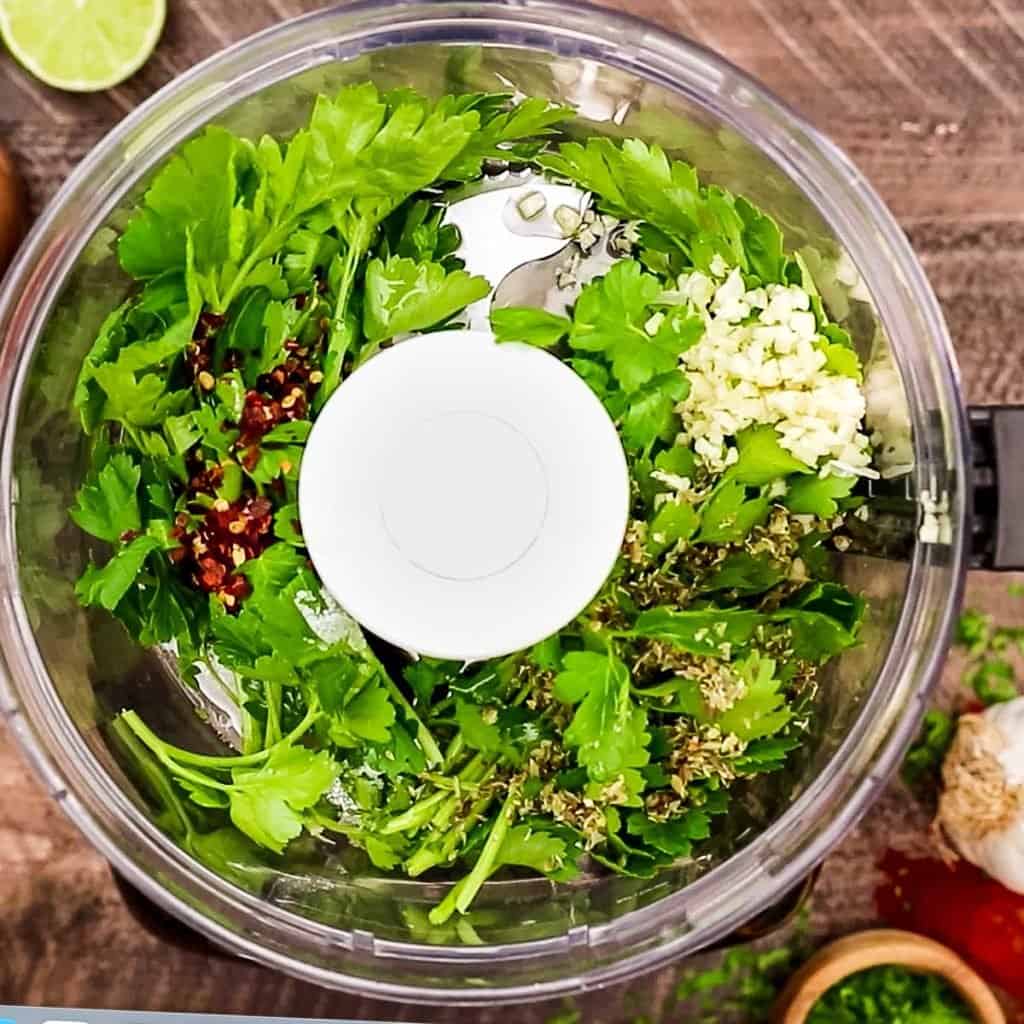 overhead showing Chimichurri ingredients in bowl of a food processor