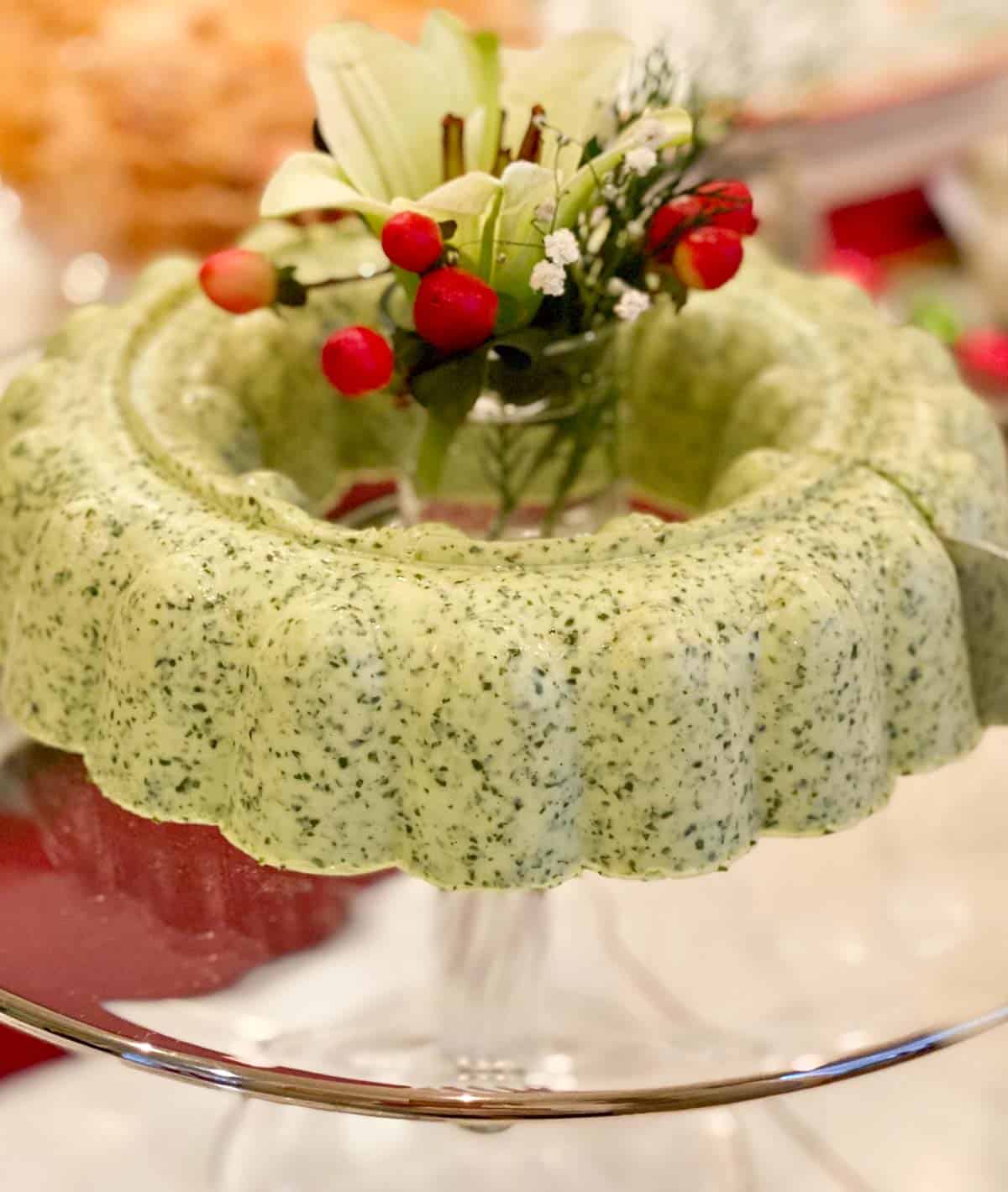 glass stand holding Cilantro Mousse ring, filled with flowers