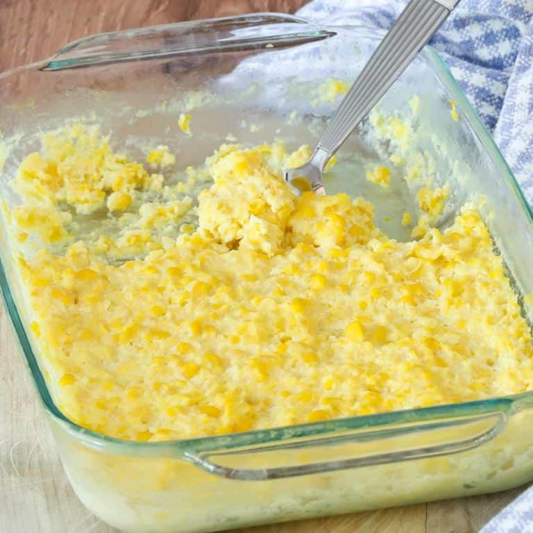 cooked corn pudding in a glass dish, with a portion removed