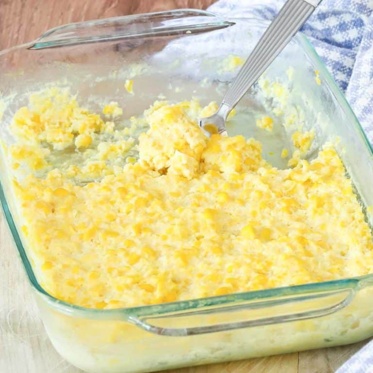 cooked corn pudding in a glass dish, with a portion removed