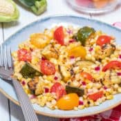 blue bowl holding grilled corn and zucchini salad with tomatoes