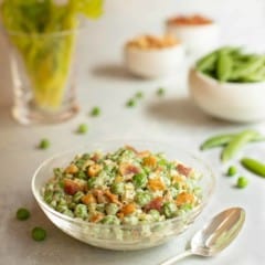 closer view of glass bowl filled with Curried Pea Salad with Bacon and Cashews, showing varied colors and textures.