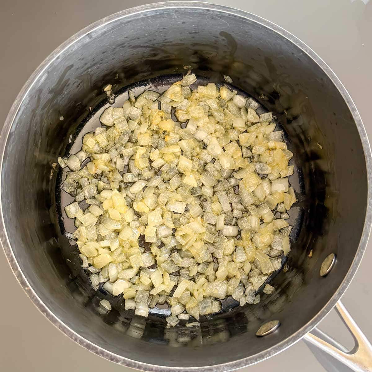 Saucepan showing sautéing chopped onions.
