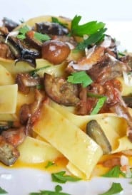 mound of pappardelle pasta covered with mushroom and eggplant sauce