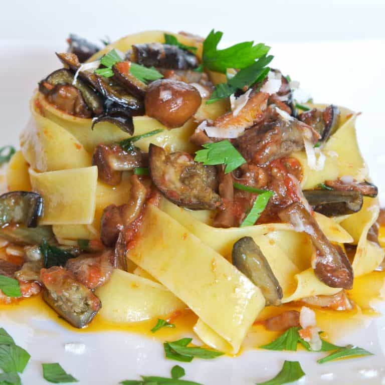 mound of pappardelle pasta covered with mushroom and eggplant sauce