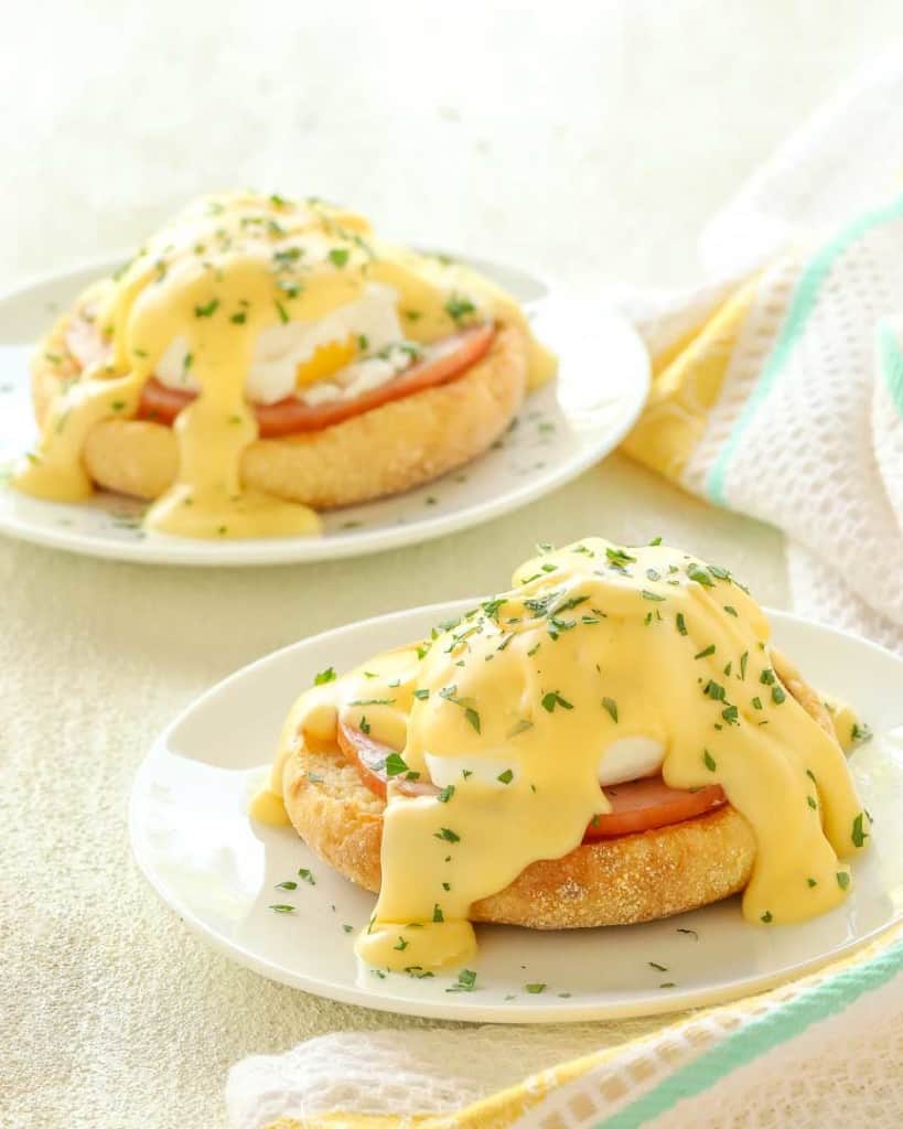 Two small plates each holding one portion of Eggs Benedict