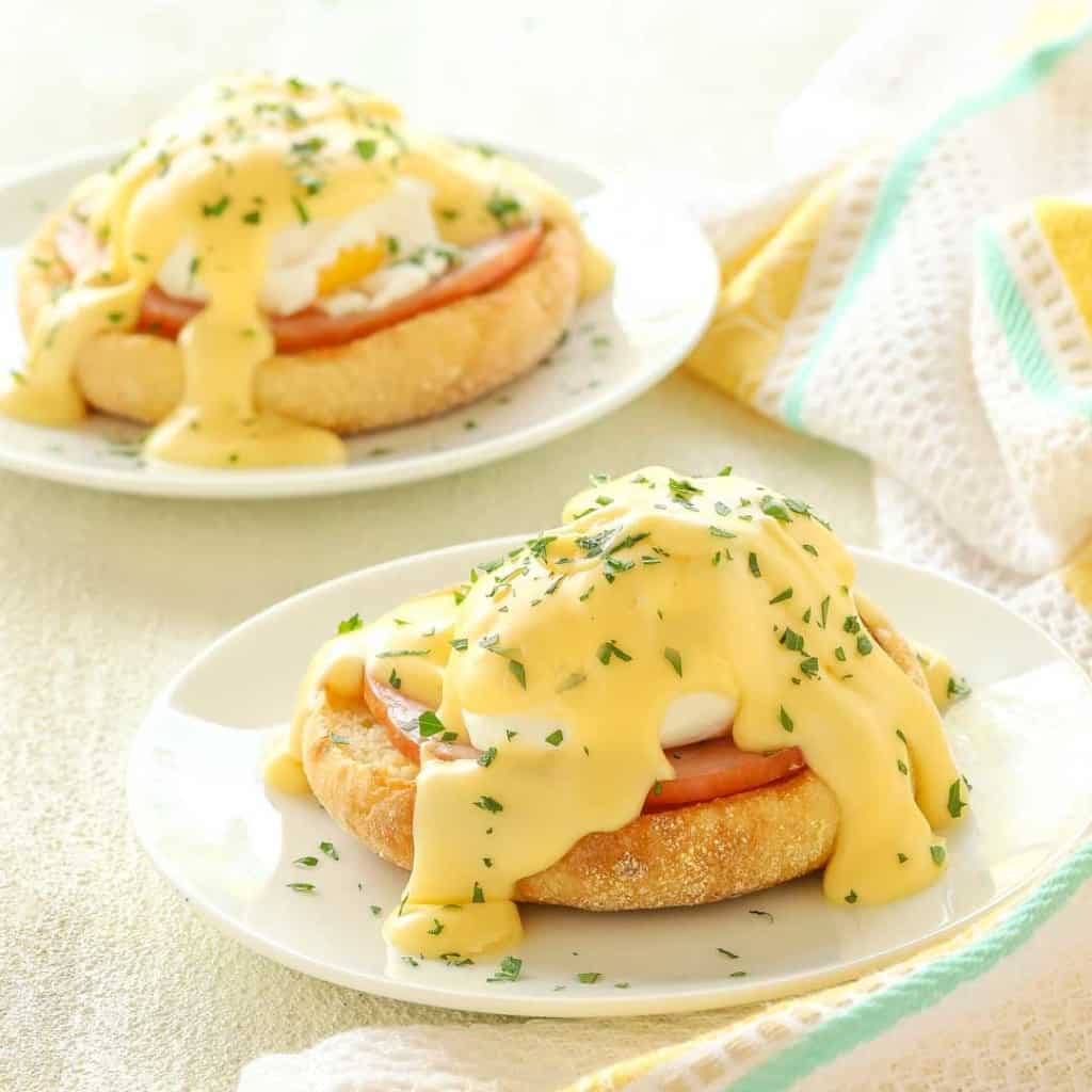 Two small plates each holding one portion of Eggs Benedict