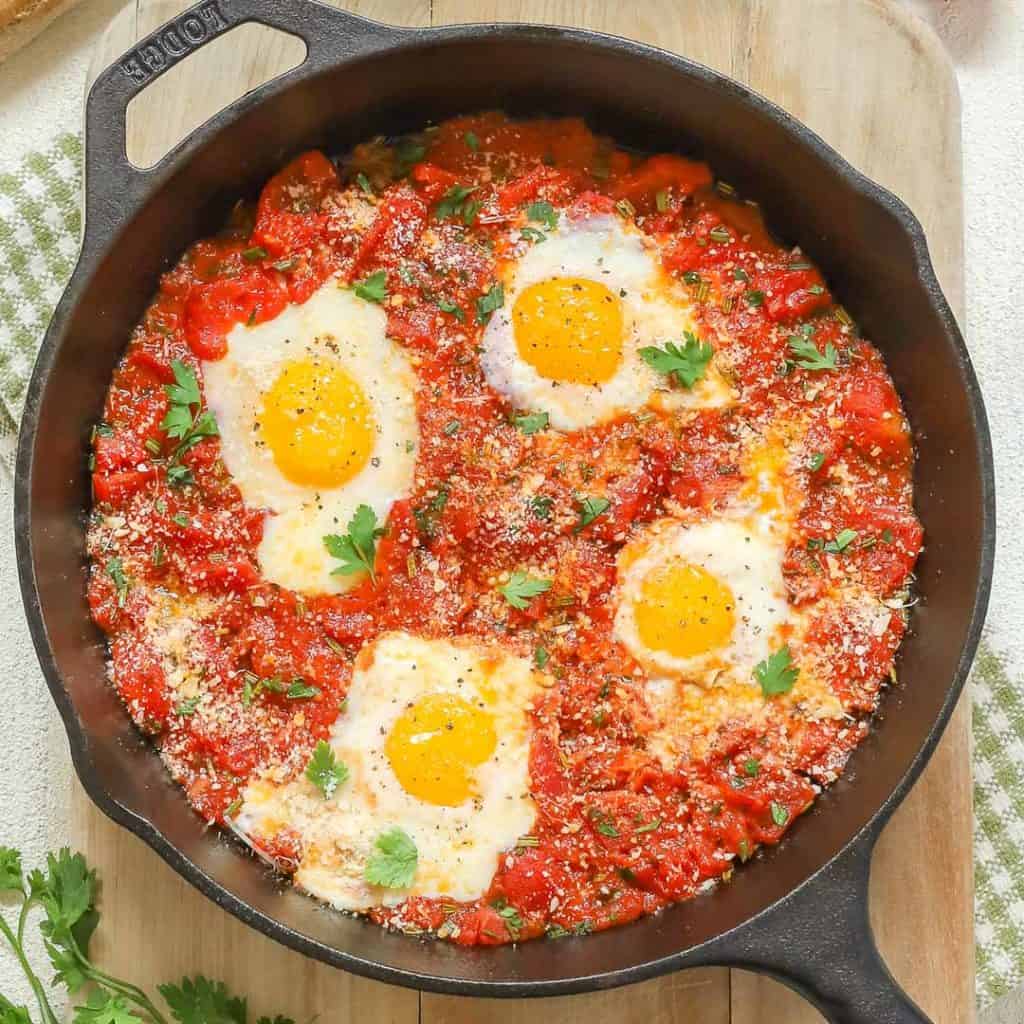 Close up, verhead of cast iron skillet holding Poached Eggs in Italian Tomato Sauce