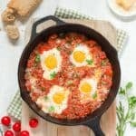 Overhead of cast iron skillet holding Poached Eggs in Italian Tomato Sauce