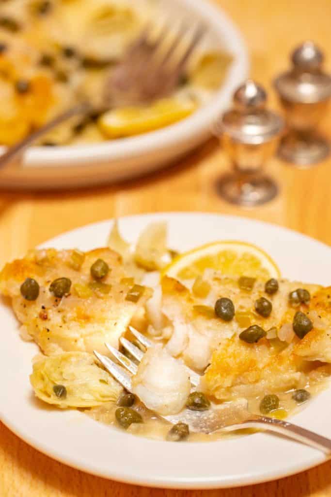 plate holding one serving of White Fish Piccata, with a bite on a fork