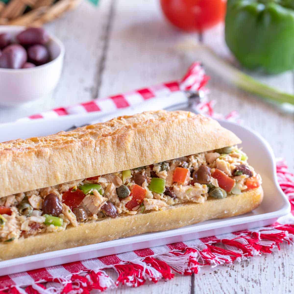 white platter holding a Pan Bagnat - crusty french baguette fiiled with Tuna Nicoise