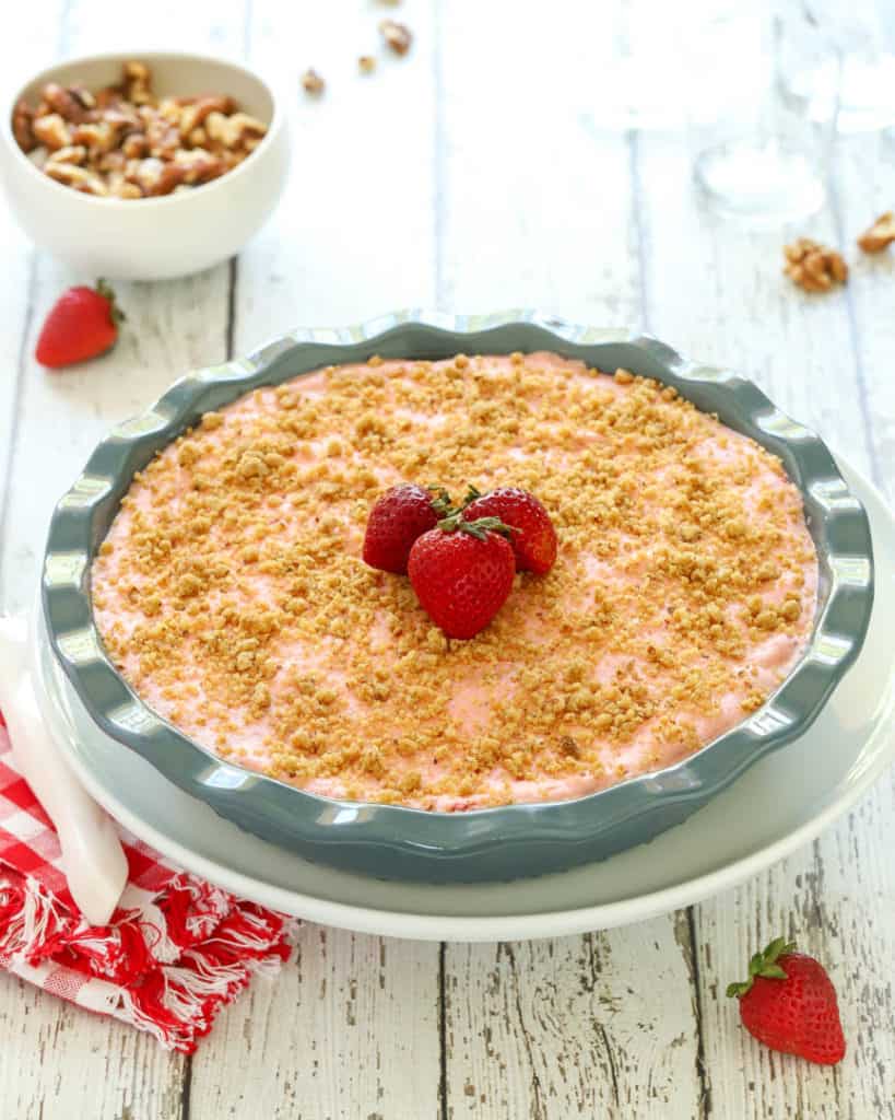 Deep dish blue pie plate holding a Frozen Strawberry PIe, garnished with 3 strawberries