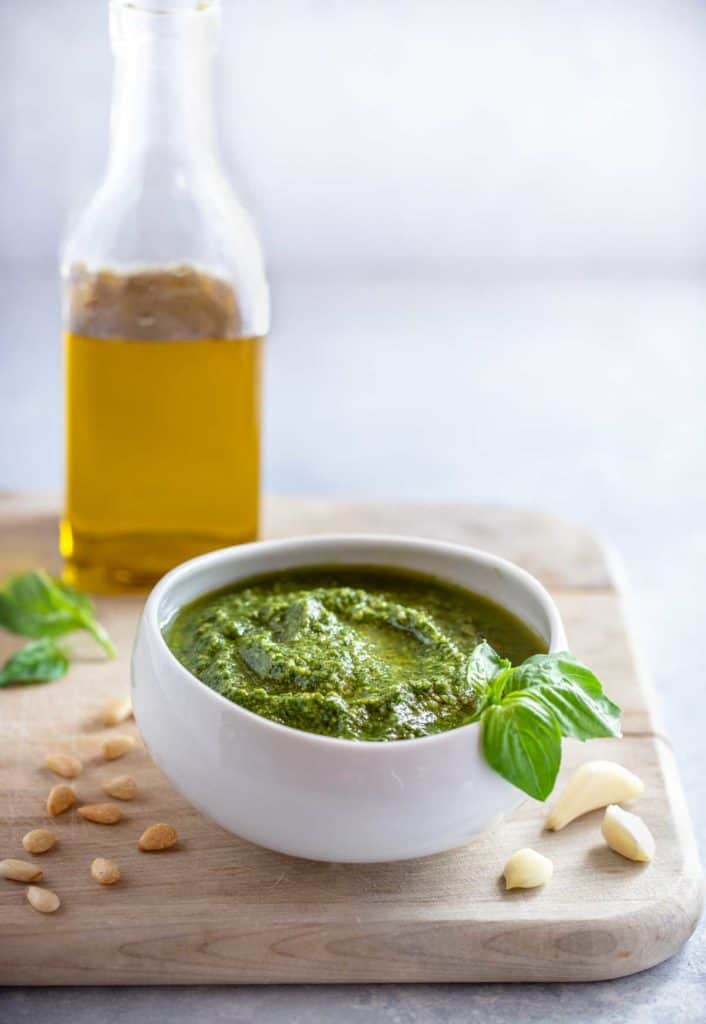 White bowl showing Pesto Genovese, with a bottle of olive oil behind it