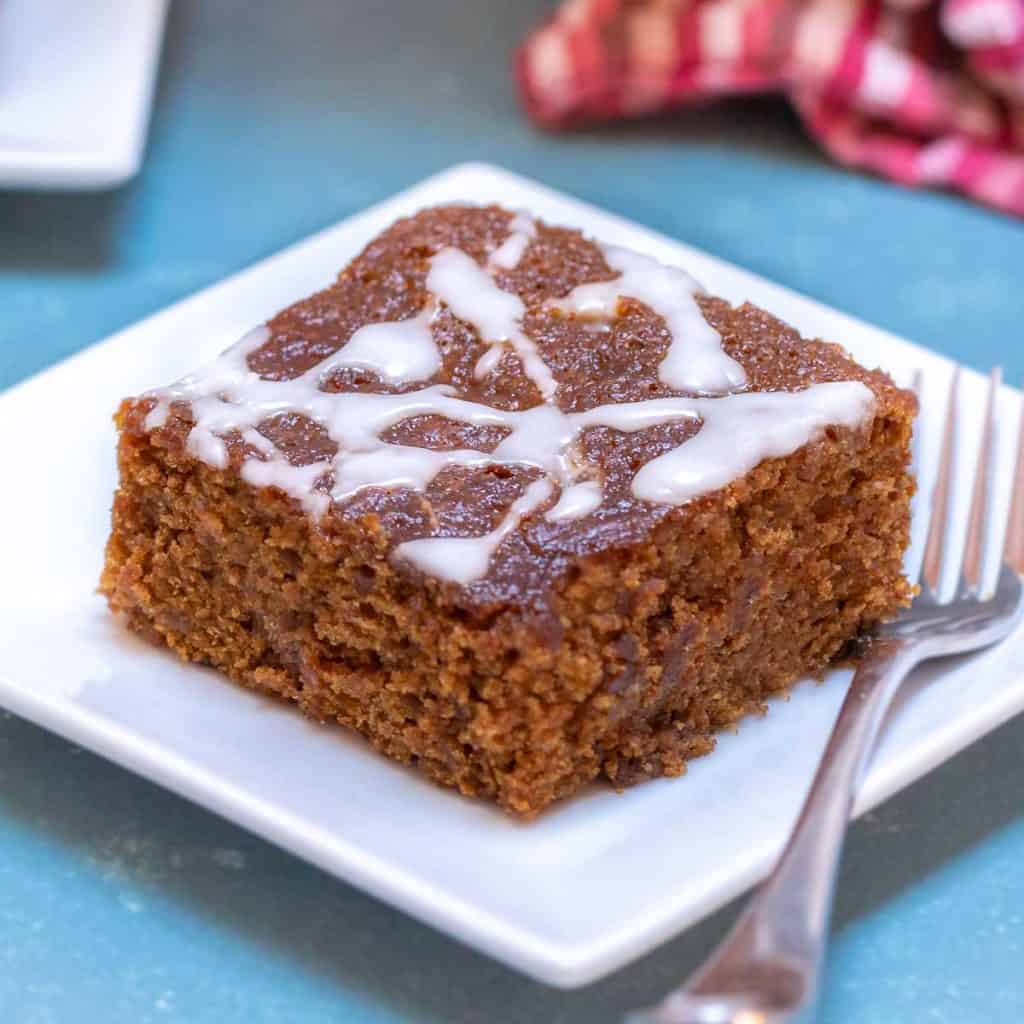 Square white plate showing a slice of Sticky Ginger Cake