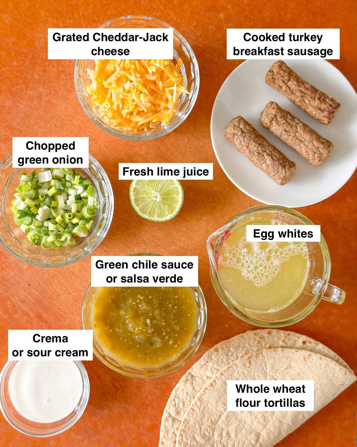 cutting board holding all 8 ingredients in green chile breakfast burritos, prepped and labeled.