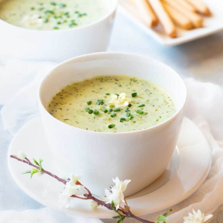 Bowl showing one serving of Pureed Green Pea Soup, with breadsticks in the background