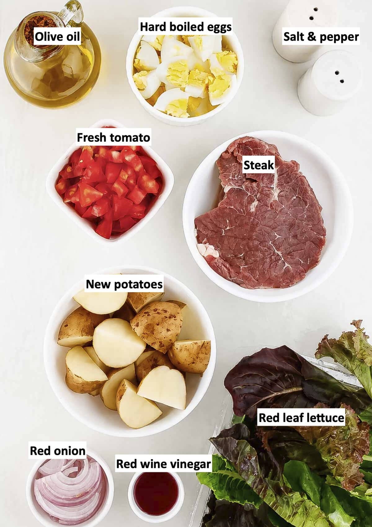 Ingredients to make grilled steak and potato salad with labels to identify each one.