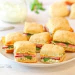 image of white plate holding several Ham and Chese Biscuits with Herb Mayo in the background